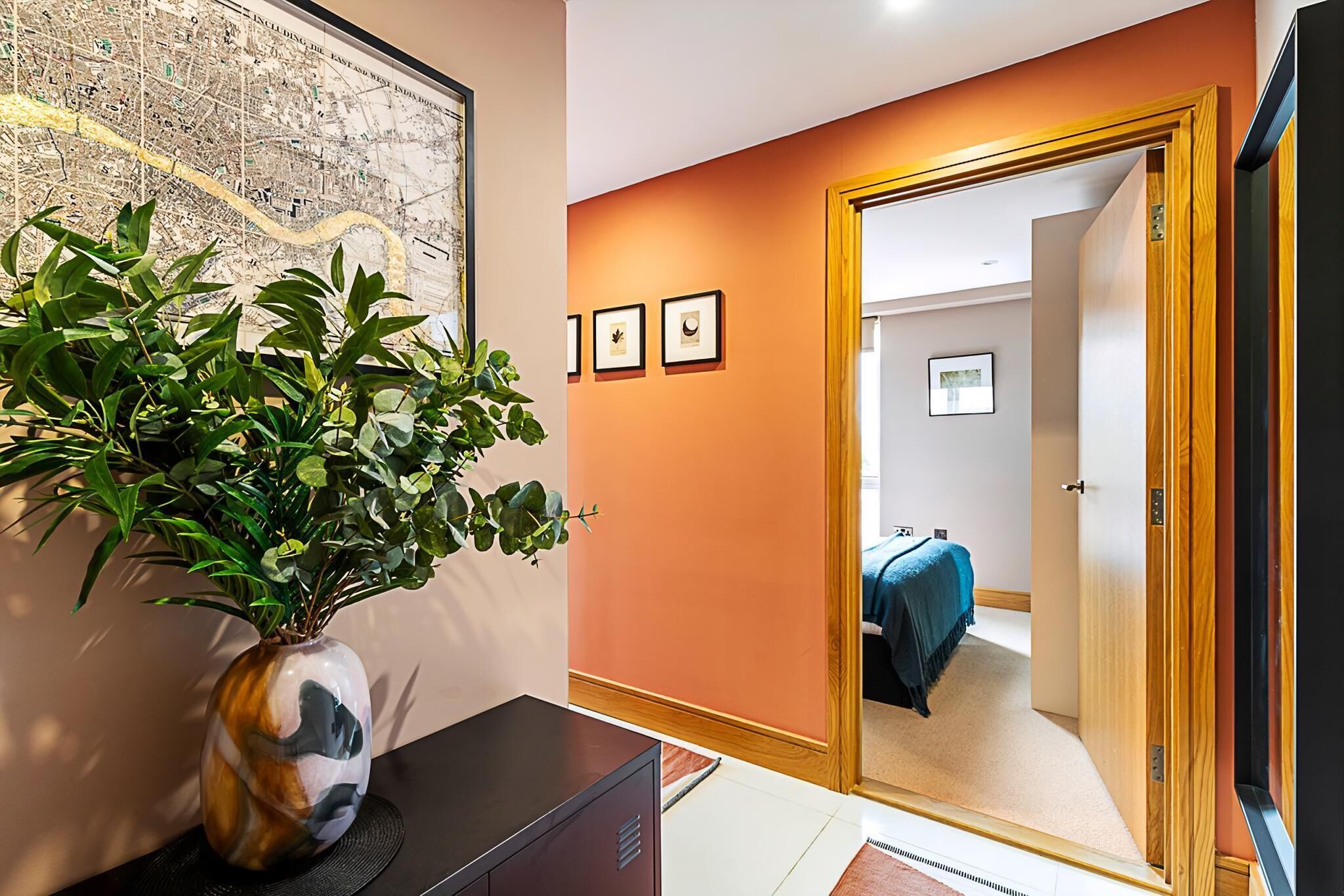A room with a map on the wall, a wooden door, and a bed with a blue cover.
