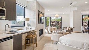 A modern hotel room with a large bed, a dining area, and a kitchen with a large window. - Snow Canyon Sanctuary #8 4 Bedroom Home (Ivins)
