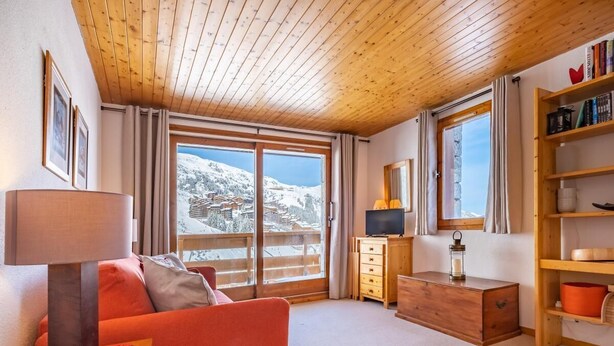 A cozy room with a wooden ceiling, a red sofa, a wooden dresser, and a bookshelf. - 5m from ski slopes, floor -5, view ski slopes, balcony, 25m², Méribel-Mottaret (Méribel - Les Allues)