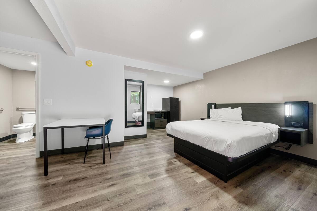 Ett modernt hotellrum med en stor säng, ett skrivbord och en stol.