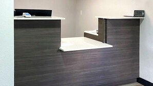A reception area with a counter, a clock, and a security camera. - Southern Suites Carrollton (Carrollton)