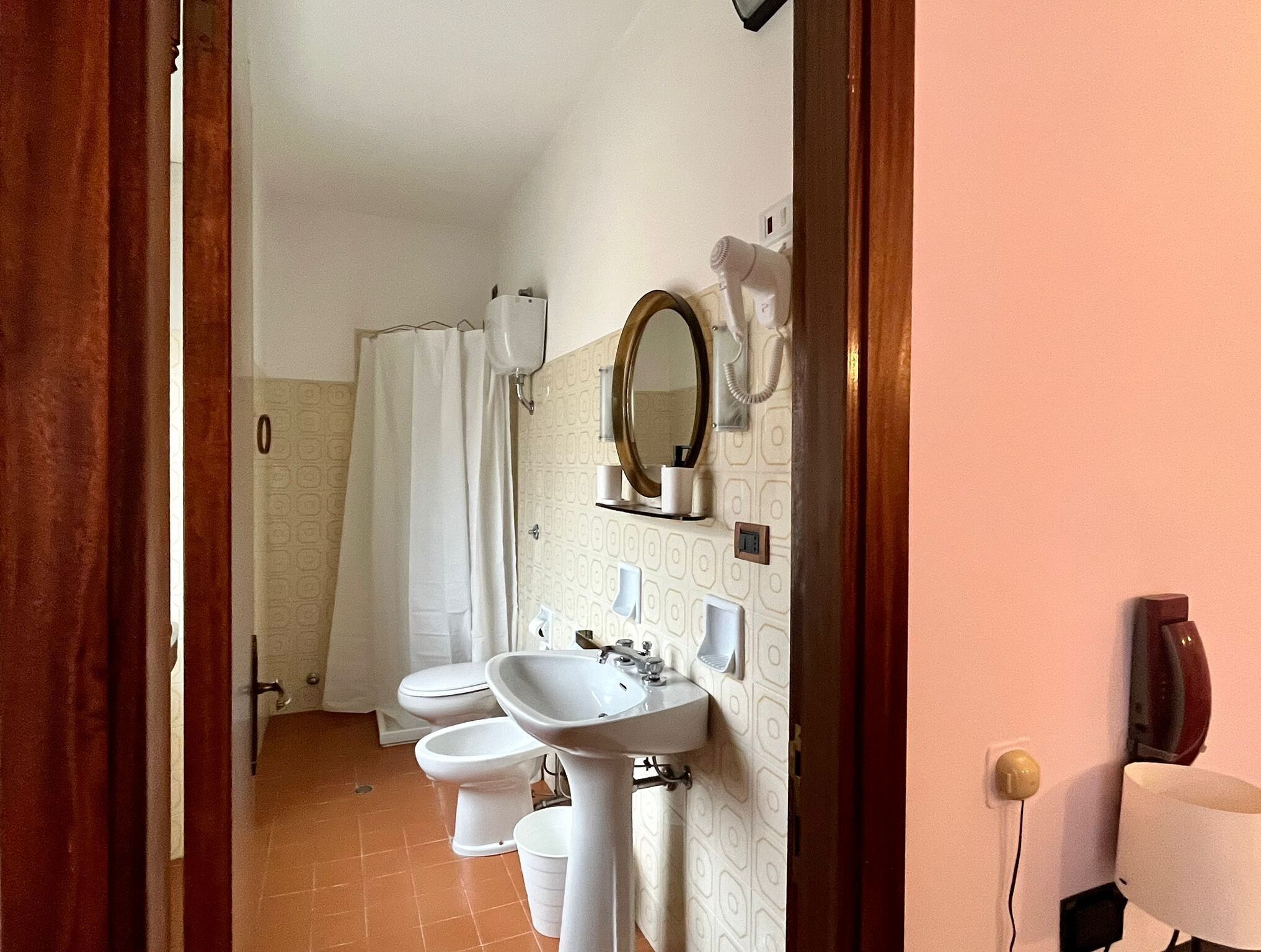 Un baño con lavamanos, espejo y dos inodoros.