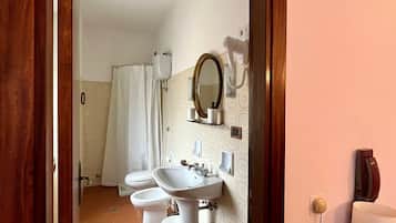 Un baño con lavamanos, espejo y dos inodoros.
