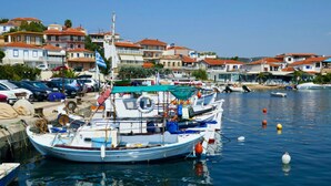 Um porto com barcos atracados, céu claro e edifícios com telhados vermelhos ao fundo.