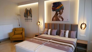Quarto moderno com uma cama grande, uma poltrona amarela e arte decorativa na parede.