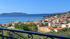 Uma cidade costeira com edifícios de telhados vermelhos, um porto de embarcações e uma vista clara do mar.
