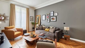 Ein modernes Wohnzimmer mit einer Couch, Sesseln, einem Couchtisch und einem Esstisch.