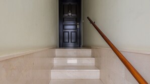 A staircase with a wooden handrail leading to a dark door with a small decorative item above it. - Luxury Workfriendly Home - Far Ocean Views (Santa Lucía de Tirajana)
