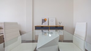 A conference room with a glass table, two white chairs, a wooden side table with framed artwork, and a white sofa in the background. - Luxury Workfriendly Home - Far Ocean Views (Santa Lucía de Tirajana)