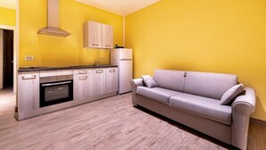 A compact kitchen with a built-in oven, a stainless steel range hood, and a white refrigerator. - Agriturismo Cascina Trevo (Spotorno)