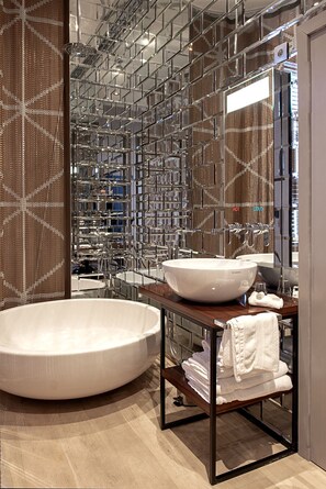 Une salle de bain moderne avec une grande baignoire sur pieds, un lavabo rond et un miroir au-dessus du lavabo.