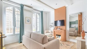 A modern living room with a sofa, a flat-screen TV, and a fireplace. - Cosy Appartement au Coeur du Cours Julien (Marseille)