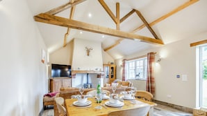A dining area with a wooden table set for four, a sofa, and a kitchen in the background. - 2 bedroom accommodation in Sloothby (Sloothby)