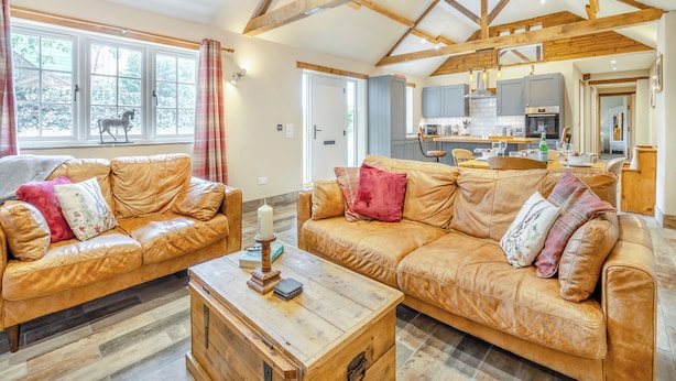 A spacious living room with leather sofas, a wooden coffee table, and a view of the kitchen. - 2 bedroom accommodation in Sloothby (Sloothby)