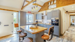 A kitchen with a central island, bar stools, a sink, and a stove. - 2 bedroom accommodation in Sloothby (Sloothby)