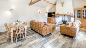 A spacious living area with a high ceiling, wooden beams, a fireplace, a television, and a dining set. - 2 bedroom accommodation in Sloothby (Sloothby)
