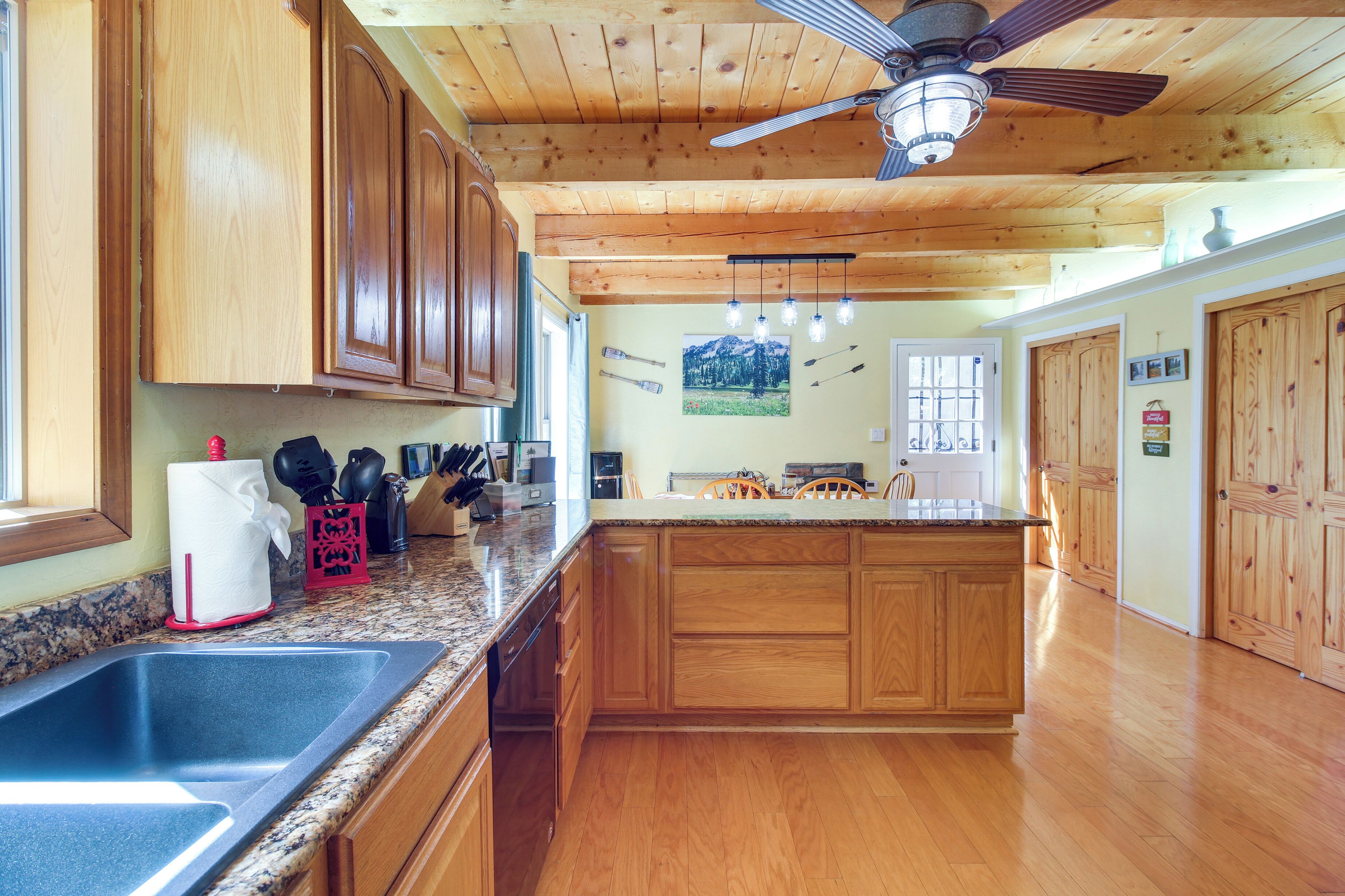 A kitchen with wooden cabinets, granite countertops, a built-in island, and a ceiling fan.