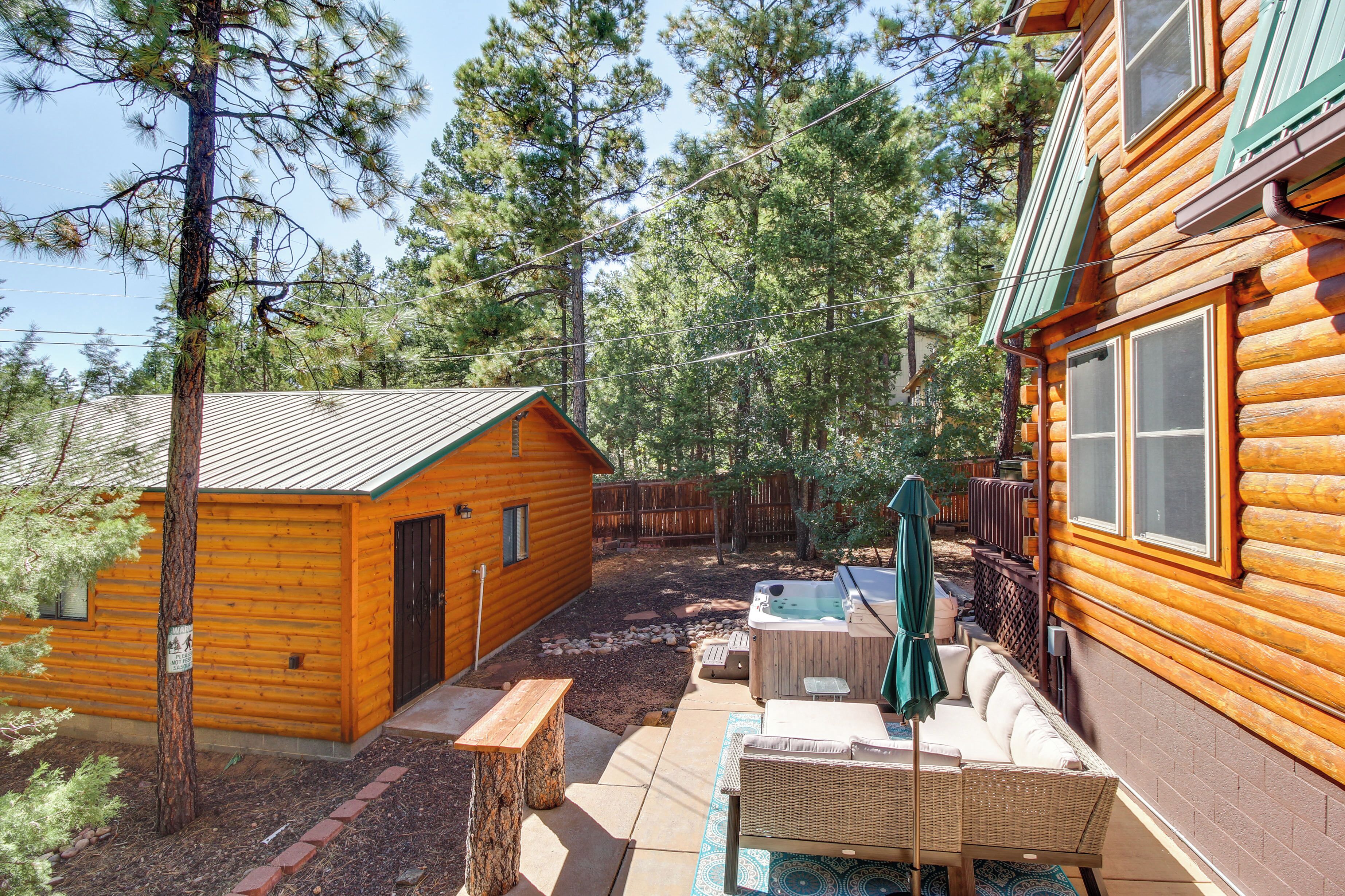 A log cabin with a patio area featuring a hot tub, outdoor seating, and a wooden deck.