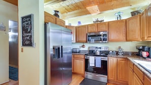 A modern kitchen with wooden cabinets, stainless steel appliances, and a chalkboard sign. - Hot Tub + Decks: Sherwood Forest Cabin (Lakeside)