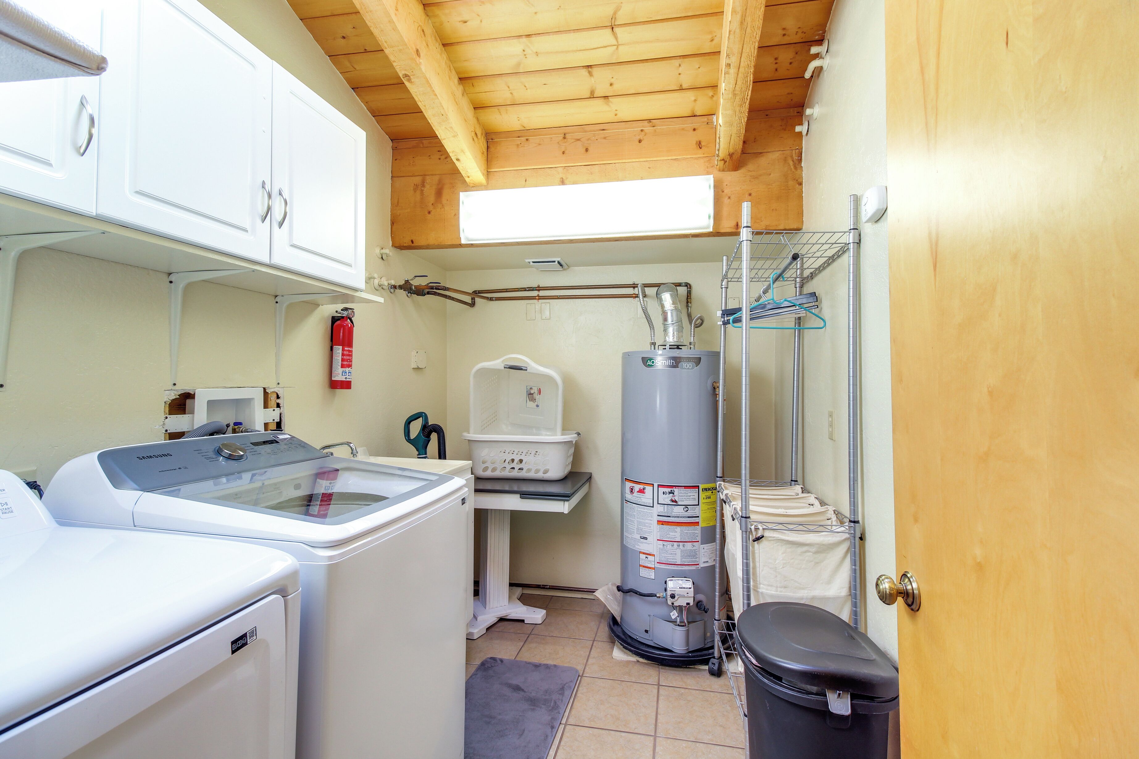 A compact laundry room with a washing machine, dryer, and a water heater.