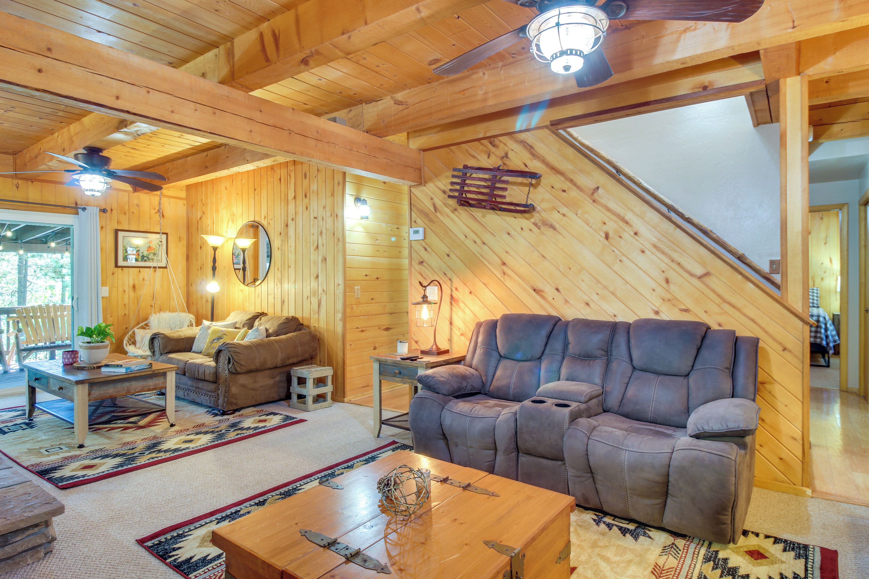 L’intérieur d’un chalet confortable, avec un canapé en cuir, un plancher en bois et un ventilateur de plafond.