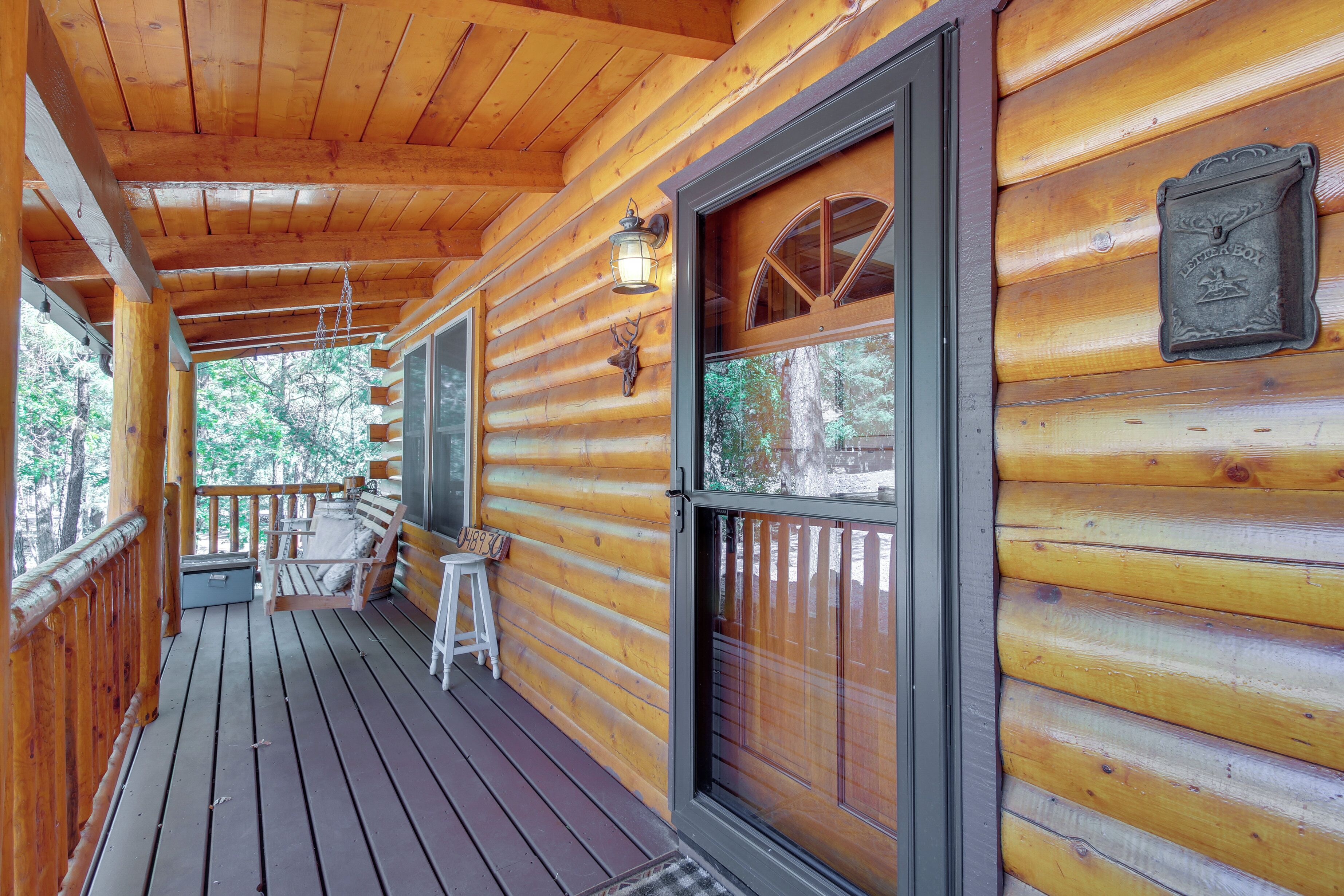 A wooden cabin with a porch, a bench, a small table, and a mailbox.