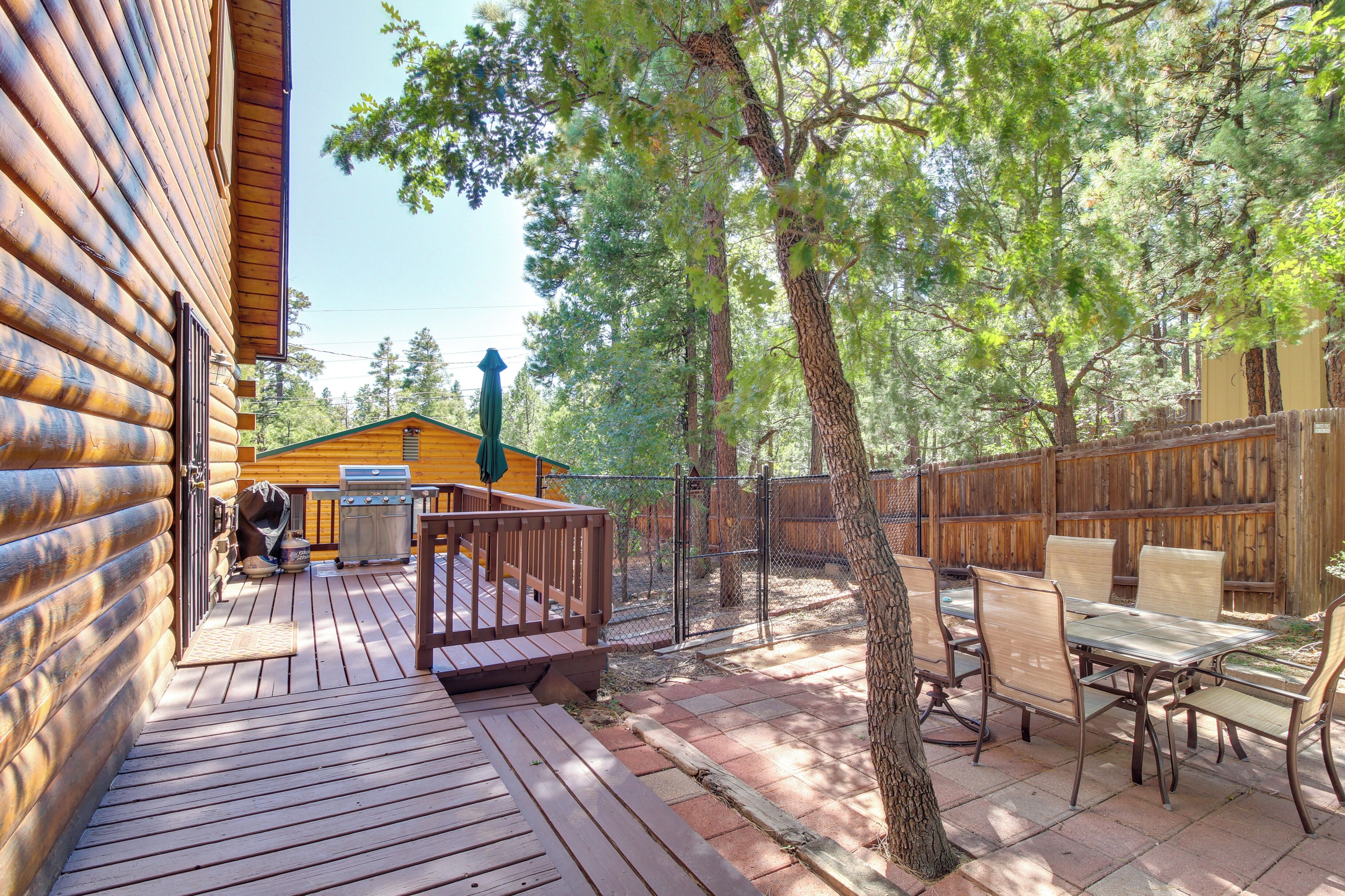 A wooden deck with a barbecue grill, outdoor furniture, and a wooden fence.