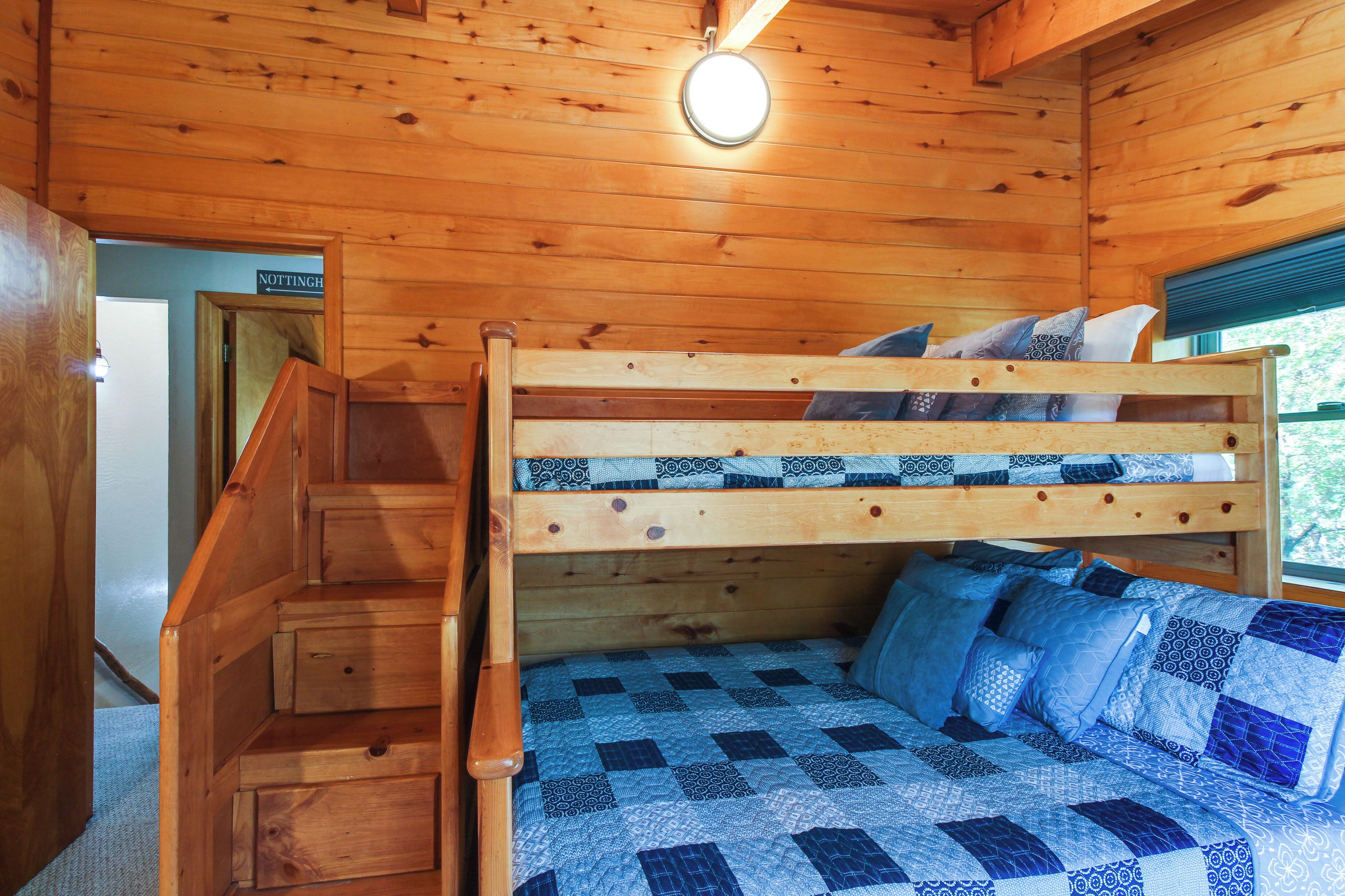 Ein Stockbett mit blau-weißer Karomattreze, Holzwänden und einer Treppe.