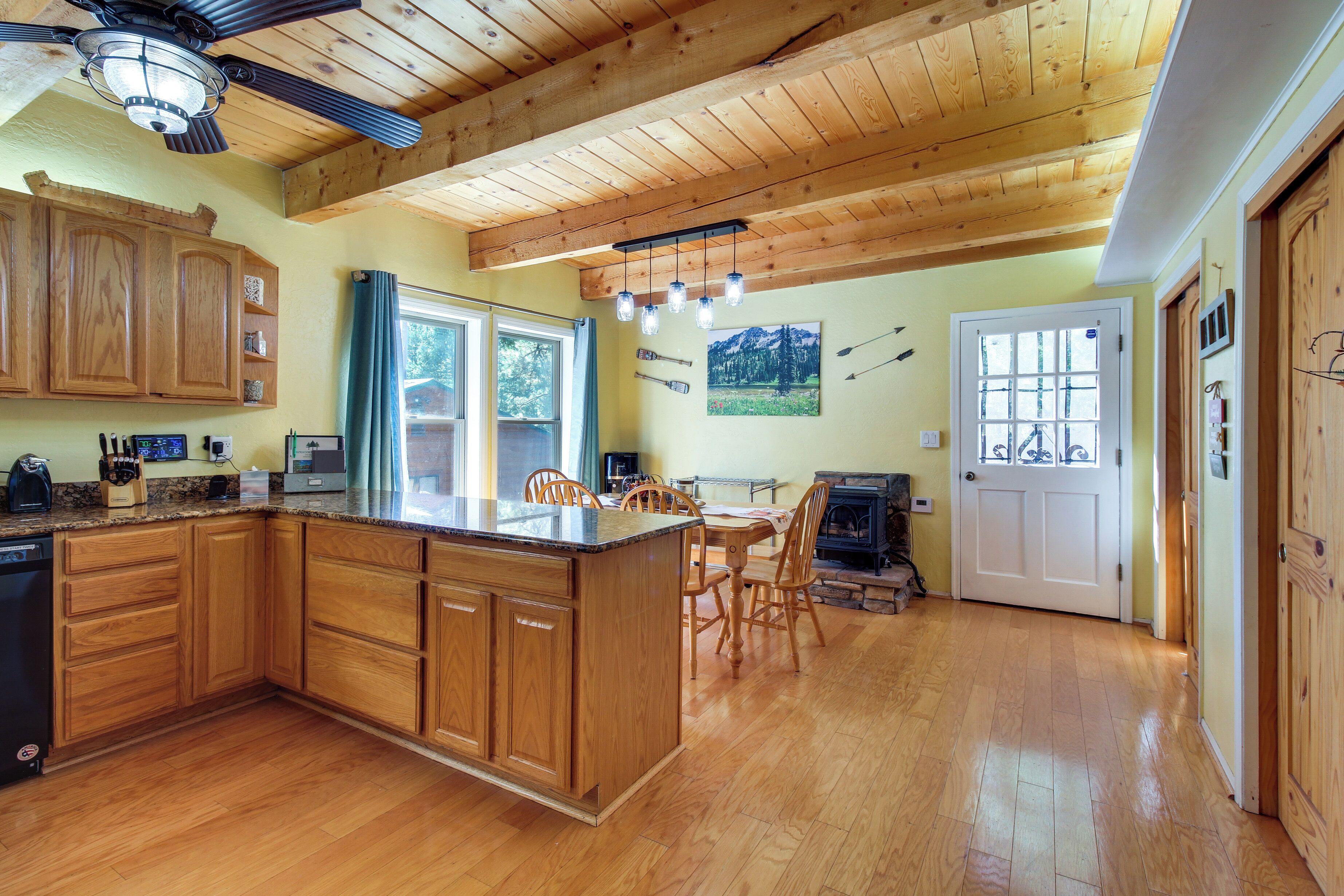 A spacious kitchen with wooden cabinets, a granite countertop, and a dining area with wooden chairs and a table.