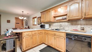 A kitchen with wooden cabinets, a microwave, a dishwasher, and a tiled backsplash.