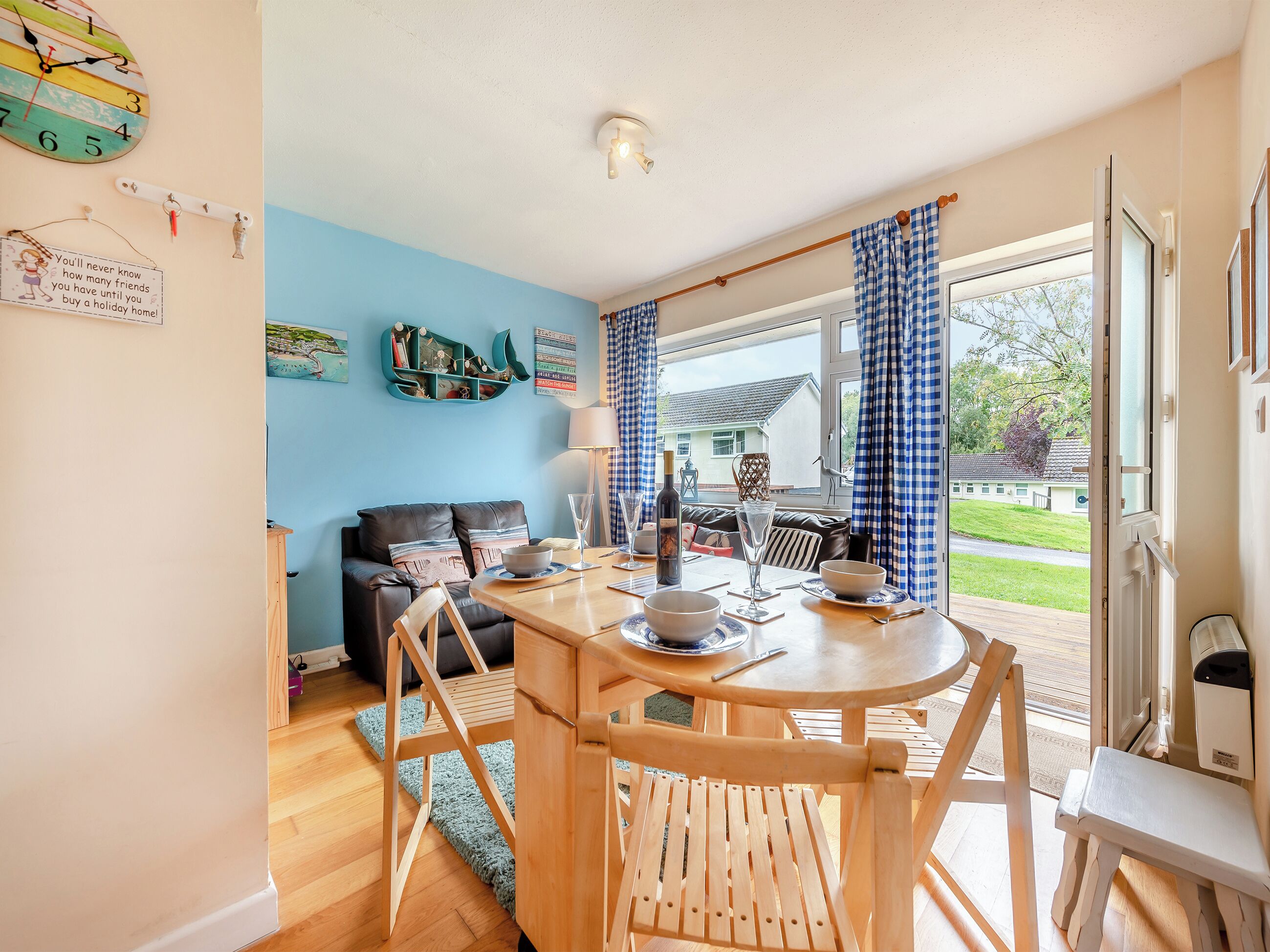 A cozy dining area with a wooden table and chairs, a blue wall, and a view of the outside.