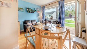 Een gezellig eetgedeelte met een houten tafel en stoelen, een blauwe wand en uitzicht op het buiten.