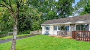 Een huis met een stenen gevel, een houten terras en een gazon.
