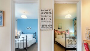 Een slaapkamer met een bed, nachtkastje, lamp en een motiverende quote op de muur.