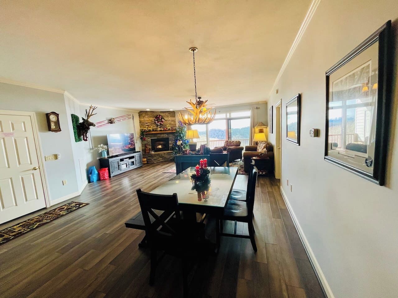 A spacious living room with a fireplace, a dining area with a table and chairs, and a kitchen in the background.