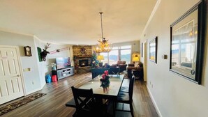 Ein großzügiges Wohnzimmer mit Kamin, einem Essbereich mit Tisch und Stühlen sowie einer Küche im Hintergrund.
