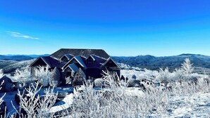 Ein Haus mit geneigtem Dach, umgeben von schneebedeckten Bäumen und blauem Himmel.