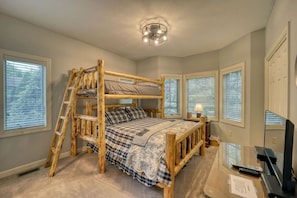 A bunk bed with a ladder, a desk with a lamp, and a TV.