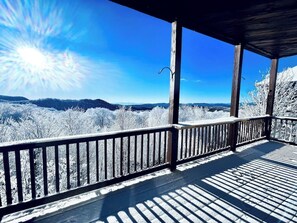 A wooden deck with a railing overlooking a snowy landscape.