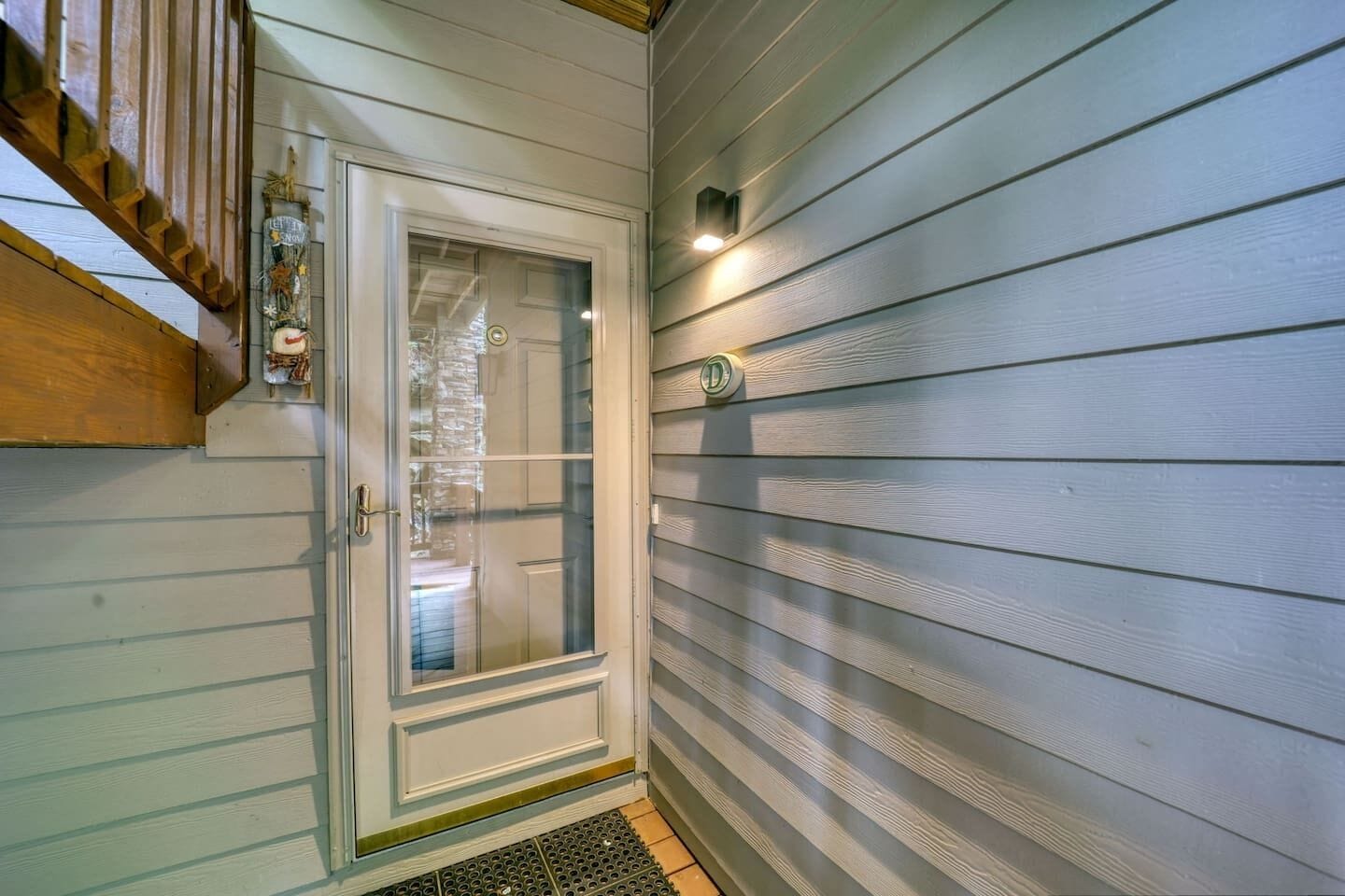 A door with a glass panel, a mailbox, and a small light fixture on the wall.