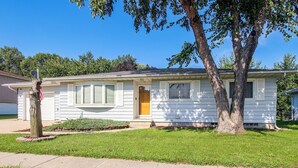Une maison de plain-pied avec un porche à l’avant, un garage et une pelouse bien entretenue.