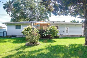 A single-story house with a front porch, a small garden with hydrangea bushes, and a tree in the foreground. - Pet-friendly Waterloo Abode w/ Deck! (Waterloo)