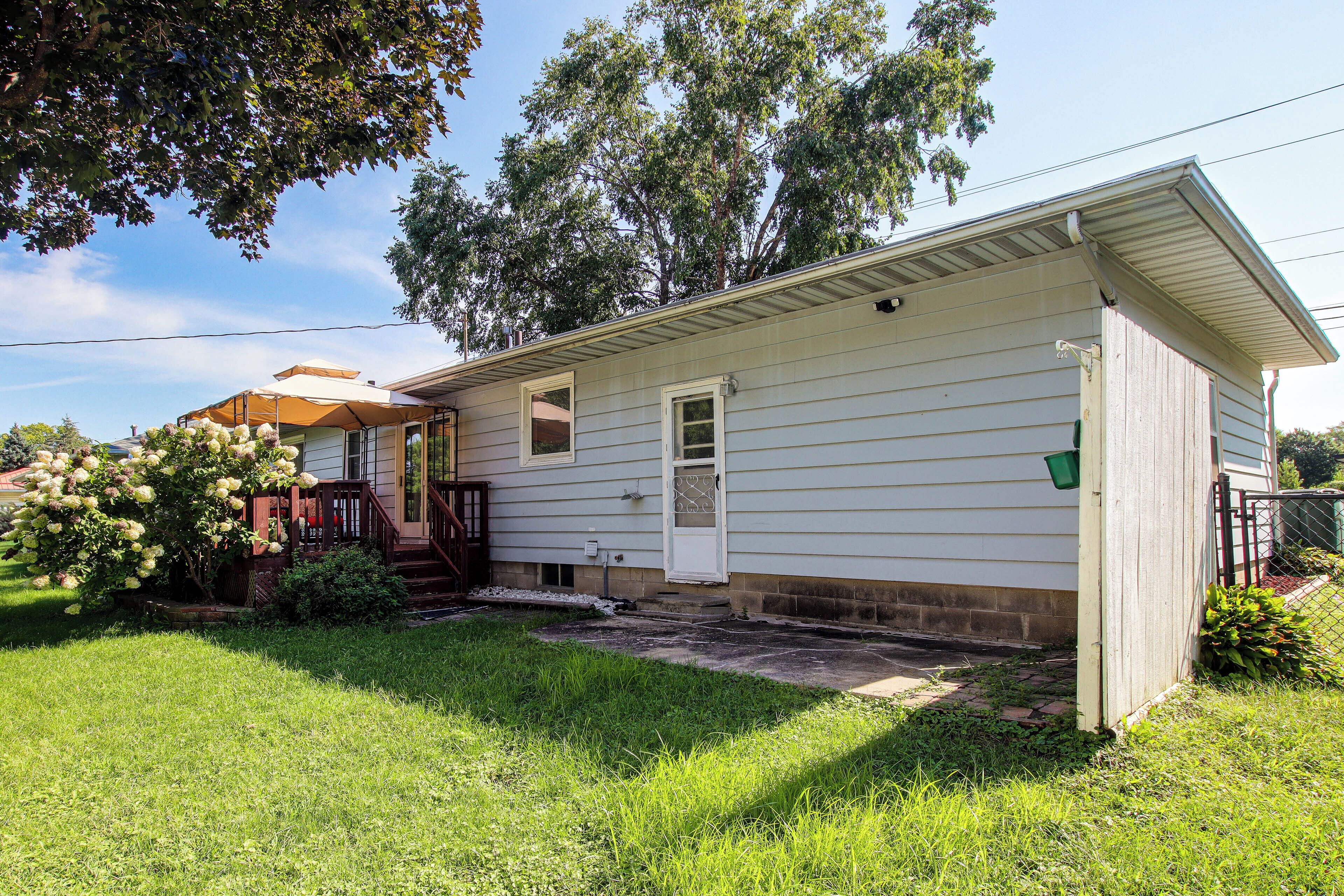 A single-story house with a front porch, a small front yard, and a tree.