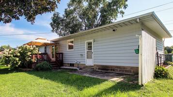 A single-story house with a front porch, a small front yard, and a tree.