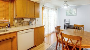 Une cuisine dotée de meubles en bois, d’un lave-vaisselle et d’un coin repas avec une table et des chaises.