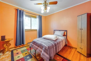 A bedroom with a bed, a wardrobe, a window with curtains, a ceiling fan, and a small table with a lamp. - Pet-friendly Waterloo Abode w/ Deck! (Waterloo)