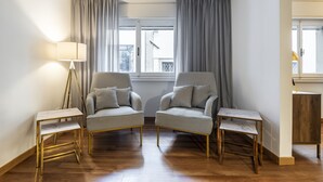 Une pièce comprenant deux fauteuils à motifs à carreaux, une petite table et un lampadaire.