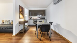 Une cuisine moderne avec un coin repas, un plancher en bois et un four encastré.