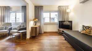 Un salon moderne comprenant un canapé, deux fauteuils, une table basse, un téléviseur et une lampe.
