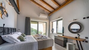 Quarto moderno com uma cama grande, cabeceira de madeira, mesa de cabeceira, espelho redondo e janela com vista.